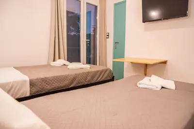 a room with two beds and a table and a window at Διαμέρισμα 2 ΣΤΗΝ ΑΓΙΑ ΜΑΡΙΝΑ in Agia Marina Aegina