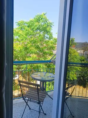 a table and a chair on a balcony at Διαμέρισμα 2 ΣΤΗΝ ΑΓΙΑ ΜΑΡΙΝΑ in Agia Marina Aegina