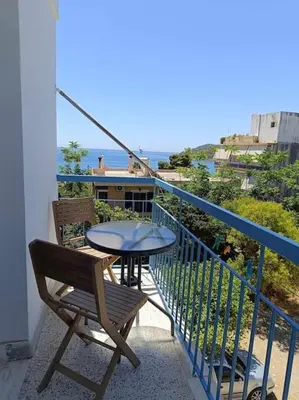 a table and a chair on a balcony with the ocean at Διαμέρισμα 3 ΣΤΗΝ ΑΓΙΑ ΜΑΡΙΝΑ in Agia Marina Aegina