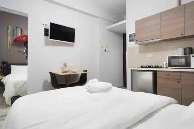 a bedroom with a white bed and a kitchen at A comfortable small studio nearby Acropolis 202 in Athens
