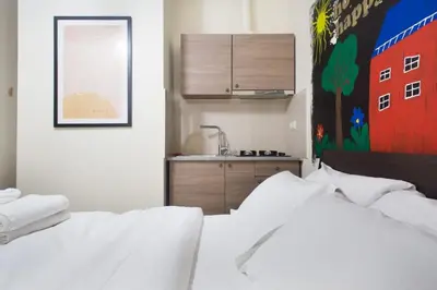 two white beds in a room with a kitchen at A comfortable small studio nearby Acropolis 203 in Athens