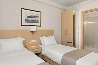 a hotel room with two beds and a window at Gallery Central Piraeus Port in Piraeus