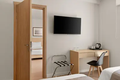 a bedroom with a chair and a television on the wall at Gallery Central Piraeus Port in Piraeus