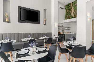 a restaurant with tables and chairs and a flat screen tv at Gallery Central Piraeus Port in Piraeus