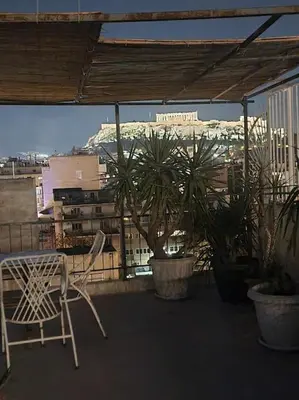 a chair on a balcony with a view of a city at Small studio under Acropolis B! in Athens