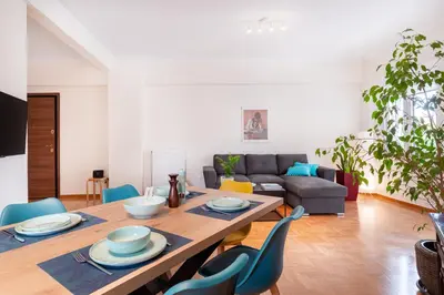 a living room with a wooden table and blue chairs at Edem Beach Apartment by Alimos Marina - Athenian Homes in Athens