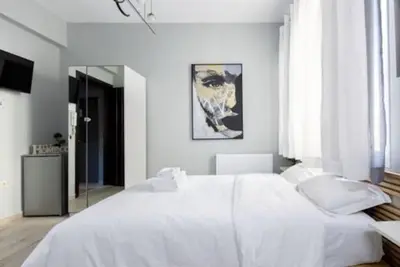a white bedroom with a large bed and a mirror at Small studio under Acropolis A! in Athens