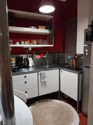 a kitchen with white cabinets and a red wall at Lucie's Apartment in Athens