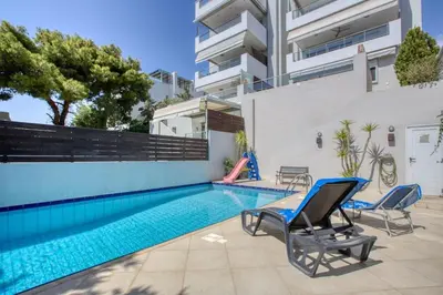 a swimming pool with blue chairs and a building at Saronida Hills private Pool in Saronida