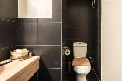 a black tiled bathroom with a toilet and a sink at Athens Seaside Retreat Floisvos in Athens