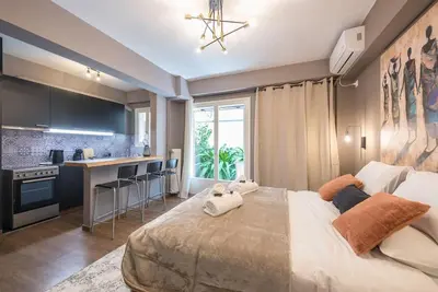 a bedroom with a large bed and a kitchen at Athens Seaside Retreat Floisvos in Athens