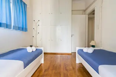 two beds in a room with white walls and wood floors at Spacious Apt Next to Marina Flisvo in Athens