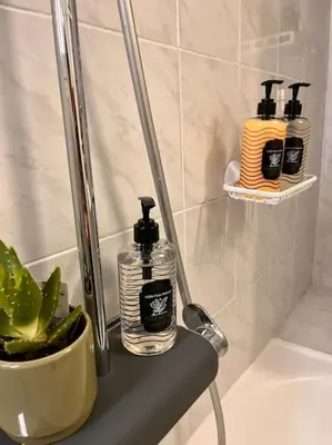 three soap bottles sitting on a shelf in a bathroom at Athena3 in Athens
