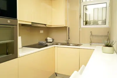 a kitchen with white cabinets and a window at Sea Breeze Beachfront Apartment VIPGreece in Athens