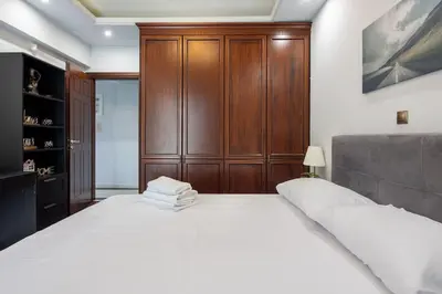 a bedroom with a large white bed and a wooden cabinet at Majestic and spacious apartment near Acropolis in Athens
