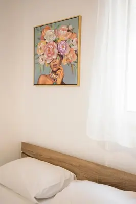 a painting of a woman with flowers above a bed at Athinais in Athens