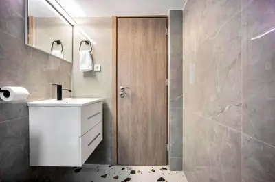 a bathroom with a sink and a wooden door at Artemis Modern Apartment in Athens