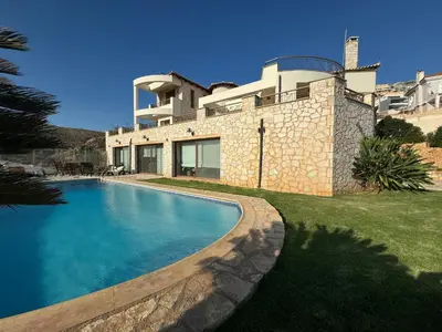 a house with a swimming pool in front of a house at Stone Villa Saronida in Saronida