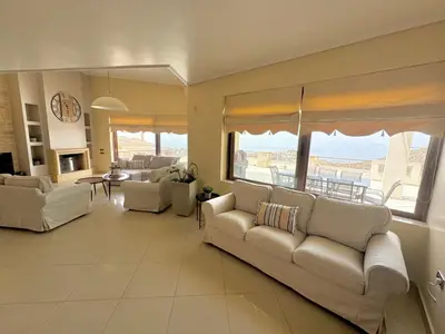 a living room with white couches and a view of the ocean at Stone Villa Saronida in Saronida