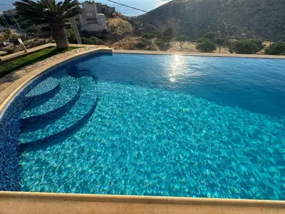 a swimming pool with stairs in the water at Stone Villa Saronida in Saronida