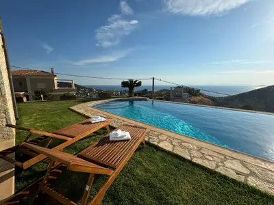 a swimming pool with two wooden benches next to the water at Stone Villa Saronida in Saronida