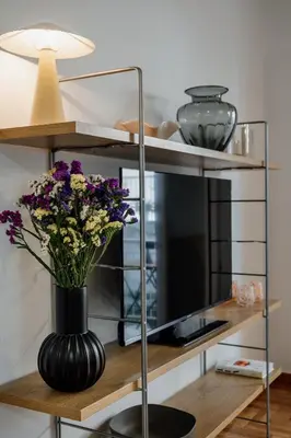 a black vase with flowers on a wooden shelf at Dylan in Athens