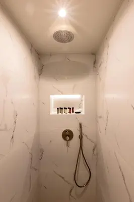 a bathroom with a shower with white marble walls at Acropolis Local Loft in Athens
