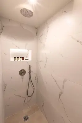 a bathroom with white marble walls and a shower at Acropolis Local Loft in Athens