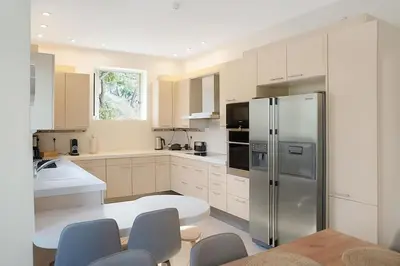 a kitchen with a stainless steel refrigerator and white cabinets at Varkiza Seaside and Views Retreat with Jacuzzi in Vari