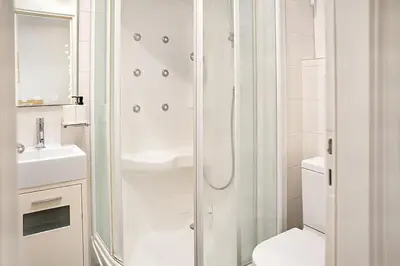 a white bathroom with a shower and a toilet at Varkiza Seaside and Views Retreat with Jacuzzi in Vari