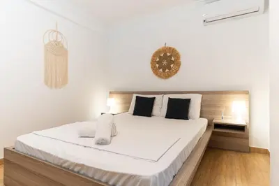 a white bedroom with a large white bed with black pillows at Spacious Peaceful Family 2BD APT in Athens