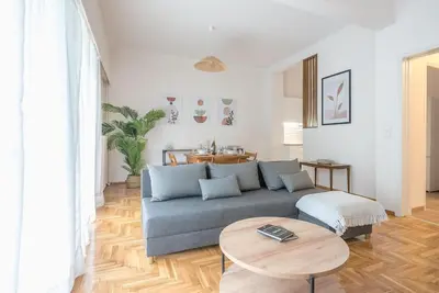 a living room with a blue couch and a table at Athens Oasis with enchanting green hill views in Athens