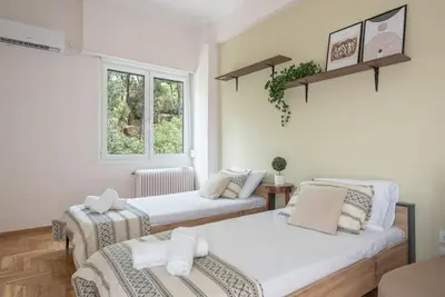 a room with two beds and a window at Athens Oasis with enchanting green hill views in Athens