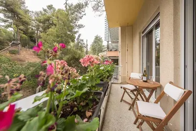 a balcony with a table and chairs and flowers at Athens Oasis with enchanting green hill views in Athens