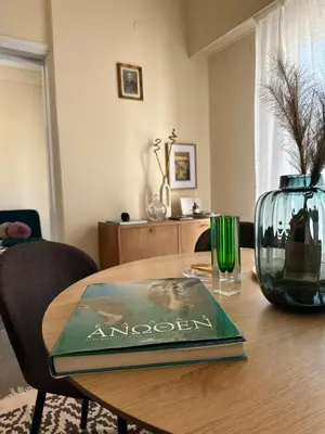 a book on a wooden table with a vase on it at Midcentury Modern Apartment in Piraeus