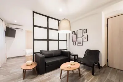 a living room with a black couch and two tables at Elegant Athens Downtown Studio in Athens