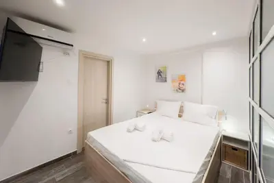 a white bedroom with a bed and a flat screen tv at Elegant Athens Downtown Studio in Athens