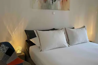 a bed with white pillows on top of it at Alfa house in the center! in Athens