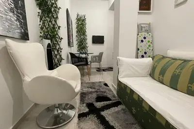 a living room with a white chair and a couch at Alfa house in the center! in Athens