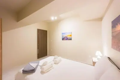 a white bedroom with a bed with towels on it at Modern Comfort Apt near centre in Athens