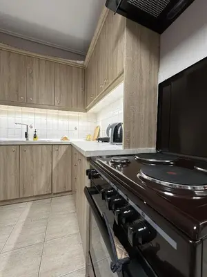 a kitchen with wooden cabinets and a black stove top oven at Piraeus Seaside Apartment Escape in Piraeus