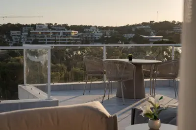 a patio with a table and chairs on a balcony at The Vouliagmeni Penthouse in Athens