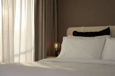a bedroom with a bed with white sheets and a window at The Vouliagmeni Penthouse in Athens