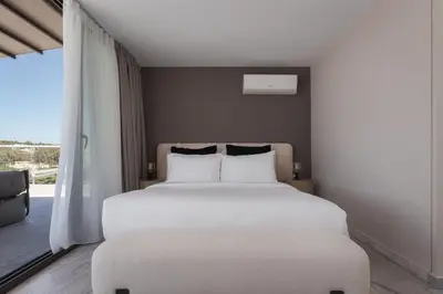 a bedroom with a large white bed and a window at The Vouliagmeni Penthouse in Athens