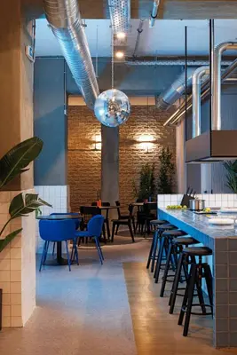 a restaurant with a bar with blue chairs and tables at Retroverse Eccentric Stay in Athens