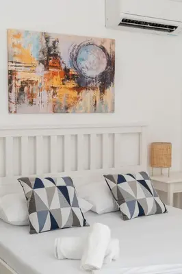 a white bed with two pillows and a painting on the wall at DOMUS by A&D Properties in Porto Rafti