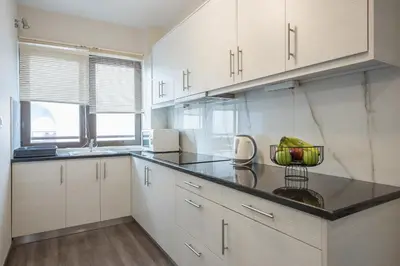 a kitchen with white cabinets and a black counter top at Apartment Steps From Historic Center Plaka in Athens