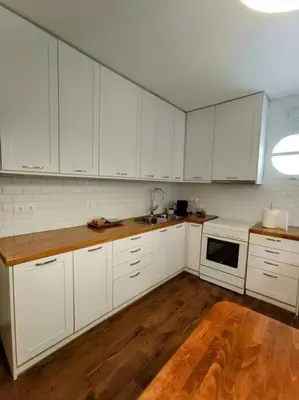 a kitchen with white cabinets and a wooden floor at Cozy Garden House in the center of Glyfada in Athens