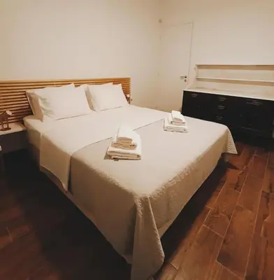 a large white bed with two towels on top of it at Cozy Garden House in the center of Glyfada in Athens