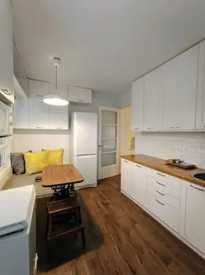 a kitchen with white cabinets and a table in it at Cozy Garden House in the center of Glyfada in Athens